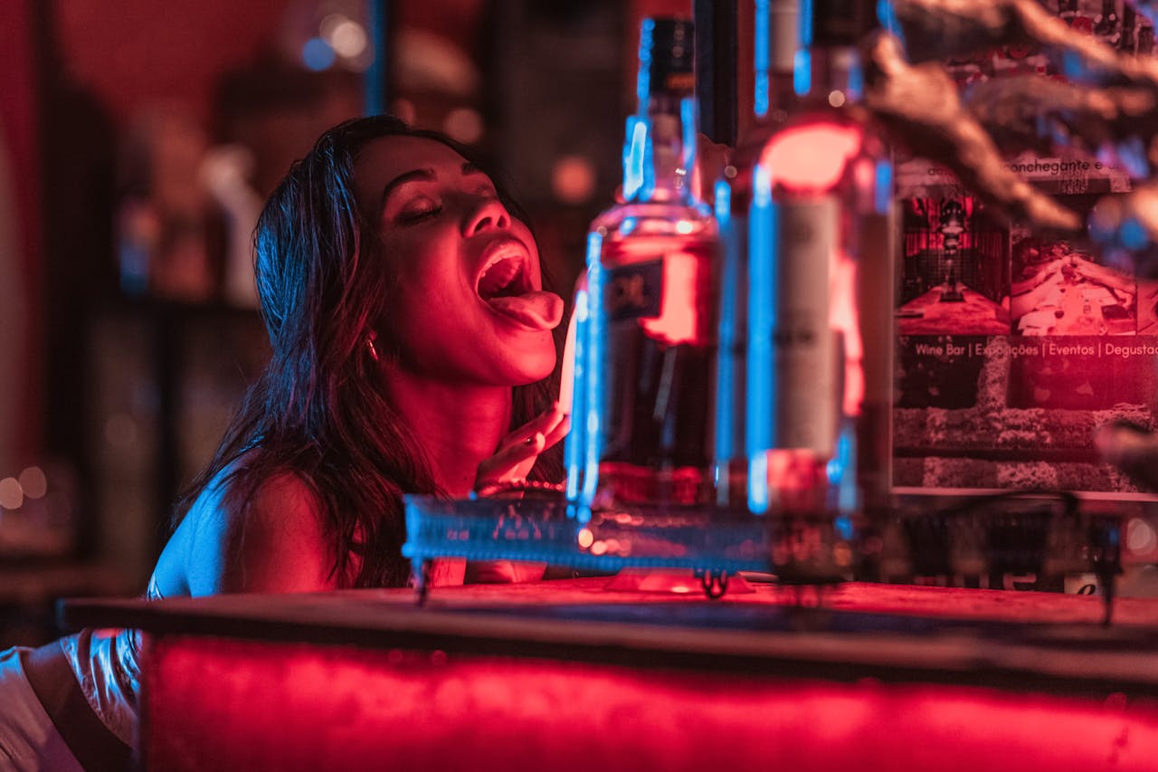 Woman enjoying nightlife in a vibrant bar setting with glowing lights and drinks in Rio de Janeiro.